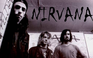 三名垃圾搖滾風格男子在帶有「NIRVANA」文字的塗鴉牆前擺姿勢。 — 涅槃 壁紙