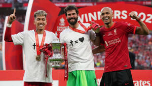三名微笑的足球員在球場上舉著獎盃。 — FIFA 世界盃 壁紙