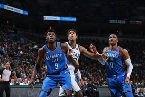 三名籃球運動員在NBA比賽中，背景有觀眾，正在進行動作。 — 桌面 壁紙