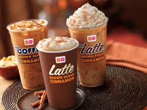三杯冰咖啡飲品，上面有鮮奶油和肉桂，放在托盤上。 — Dunkin Donuts 壁紙