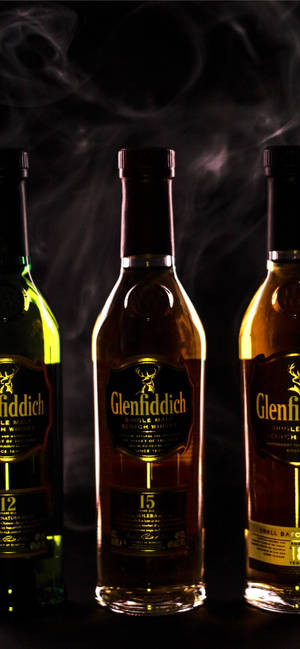 三瓶 Glenfiddich 威士忌在黑暗環境中帶有煙霧。 — iPhone 18 Pro 壁紙