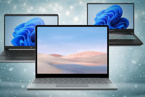 三部筆記型電腦在雪景和燈光背景下展示Windows 11桌布。 — 最佳筆電 壁紙