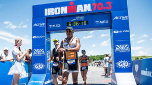 運動員在觀眾歡呼聲中越過Ironman 70.3終點線。 — 運動 壁紙