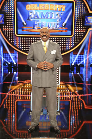 Steve Harvey在Celebrity Family Feud遊戲節目佈景中微笑，燈光璀璨。 — 家庭 壁紙