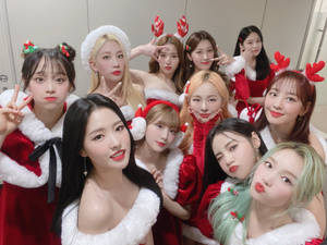 九位K-pop偶像穿著聖誕老人服裝，在室內戴著馴鹿角擺姿勢。 — 聖誕美學 壁紙