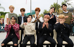 九位年輕男士穿著時尚服裝，在戶外與棕櫚樹一起拍手擺姿勢。 — Nct 127 壁紙