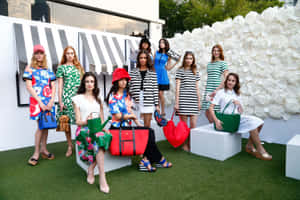 模特兒穿著彩色連衣裙和手提包在戶外白色方塊上擺姿勢。 — Kate spade 壁紙