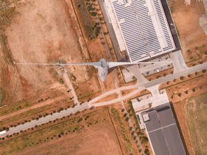 從上方俯瞰乾旱土地上的風力渦輪機和太陽能農場，有道路和建築物。 — 能量 壁紙