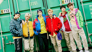 五位身穿潮流街頭服的年輕男子在綠色貨櫃前擺姿勢。 — Nct 127 壁紙