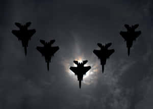 五架戰鬥機在陰暗多雲的天空中編隊飛行，太陽在背後。 — 空軍 壁紙