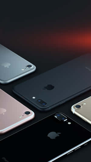 五部不同顏色的Apple iPhone對角線排列在深色表面上，帶有紅色燈光。 — iPhone 6s Plus 壁紙