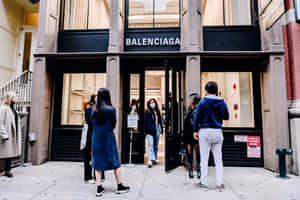 人們在 Balenciaga 零售店入口外排隊等候。 — 巴黎世家 壁紙