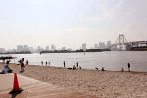 人們在海灘上享受陽光燦爛的一天，背景是城市天際線和橋樑。 — 塔橋 壁紙