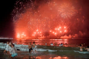 海洋中的人群在夜間觀看紅色煙火 — 新年快樂 2020 壁紙