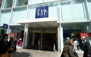 購物者走過一間GAP服裝店，窗戶上可見減價標誌。 — 16:10 壁紙