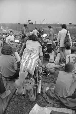 戶外音樂節的人群，有摩托車和舞台。 — Woodstock 壁紙