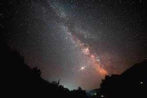 銀河系與流星掠過山巒剪影的夜空 — 星星 壁紙
