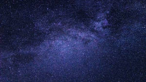 銀河系在黑暗的夜空中閃爍著紫色和藍色的星星。