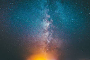 銀河系在繁星點點的夜空中散發著青綠色和橙色的色調。 — 海洋藍 壁紙