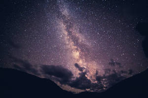 銀河系在繁星點點的夜空下，於山頂上方閃耀。 — 紫色玫瑰 壁紙