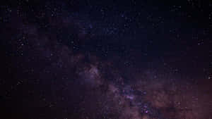 銀河系在黑暗的夜空中閃耀著紫色和藍色的星星。 — 簡約暗黑美學 壁紙