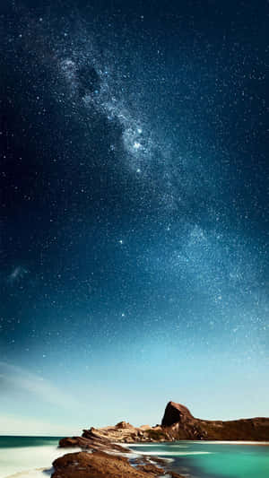 夜晚，銀河系在岩石海岸和碧綠海水上方。 — 海洋 壁紙