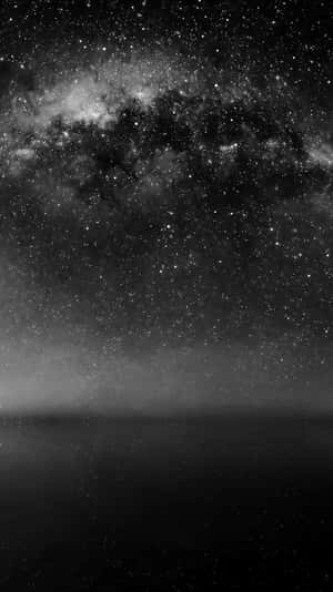 銀河系在星空下黑暗地平線上方閃耀。 — 夜空 壁紙