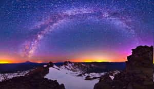 積雪的山峰在璀璨星空下，銀河在其上方拱起。 — 冬季風景 壁紙