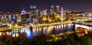 充滿活力的夜景，閃耀的摩天大樓和倒映的河流。 — 城市 壁紙