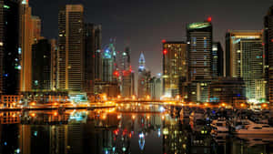 夜晚的城市天際線，摩天大樓和船隻倒映在水中。 — 房地產 壁紙