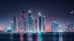夜間城市景觀，摩天大樓燈火通明，星空倒映在水中。 — 杜拜 壁紙