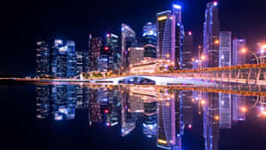 夜間城市天際線，燈火通明的摩天大樓和橋樑倒映在水中。 — 夜景城市 壁紙