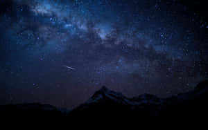 積雪的山峰在星空下，有一顆流星劃過。 — 暮光 壁紙