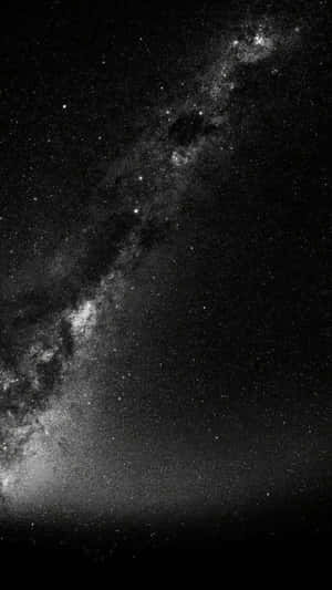 銀河系在繁星點點的夜空中以黑白色彩閃耀。 — 黑灰 iPhone 壁紙