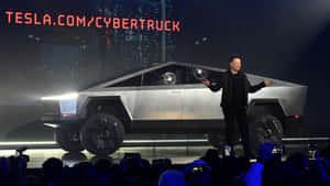 伊隆·馬斯克在燈光明亮的舞台上展示 Tesla Cybertruck，觀眾在拍攝。 — 特斯拉 壁紙