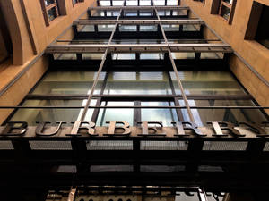 現代城市環境中帶有玻璃面板和金屬標誌的 Burberry 商店入口。 — Burberry 壁紙
