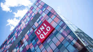現代玻璃建築，彩色面板和UNIQLO標誌，藍天白雲下。 — Pro Display XDR 壁紙