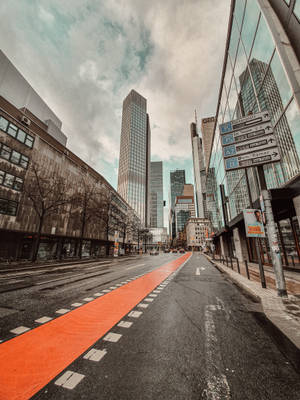 城市街道，有橙色自行車道和高大的玻璃建築，天空多雲。 — 城市風景 壁紙