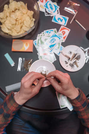 一個人在有Uno卡和小吃的桌子上捲煙。 — 喜悅 壁紙
