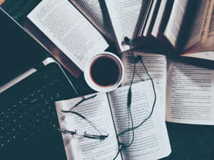 打開的書本、眼鏡、咖啡和筆記型電腦放在深色書桌上供學習使用。 — 讀書 壁紙
