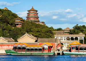 綠色船隻停泊在湖邊的傳統中國宮殿建築群。 — 丘陵景觀 壁紙