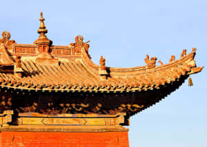 藍天下，傳統中國寺廟的屋頂，鋪著金色瓦片，裝飾著脊獸。 — 城堡動畫 壁紙