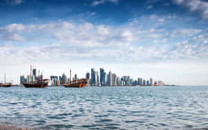 傳統木製單桅帆船在擁有高樓大廈的現代城市天際線附近航行。 — 科威特 壁紙