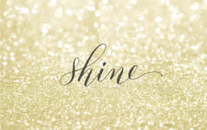 金色亮粉背景上的黑色草書「shine」一詞。 — 16:10 壁紙