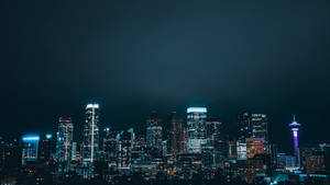 夜間城市天際線，建築物閃閃發光，一座燈光塔樓。 — 達拉斯獨行俠 壁紙