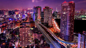 夜晚繁忙的城市，燈火通明的建築物和移動車輛的光跡。 — 日式 壁紙