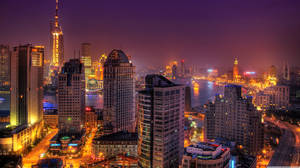 黃昏時分，高樓大廈和河流閃耀的城市天際線。 — 城市風景 壁紙