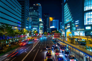 夜間城市街道，有發光的建築物和移動的車燈。 — 日本 壁紙