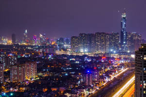 夜間城市，有燈光建築物和移動車輛的光跡。 — 尚氣 壁紙
