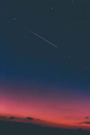 一顆流星劃過黑暗山丘上方佈滿星星的暮色天空。 — 簡約 壁紙